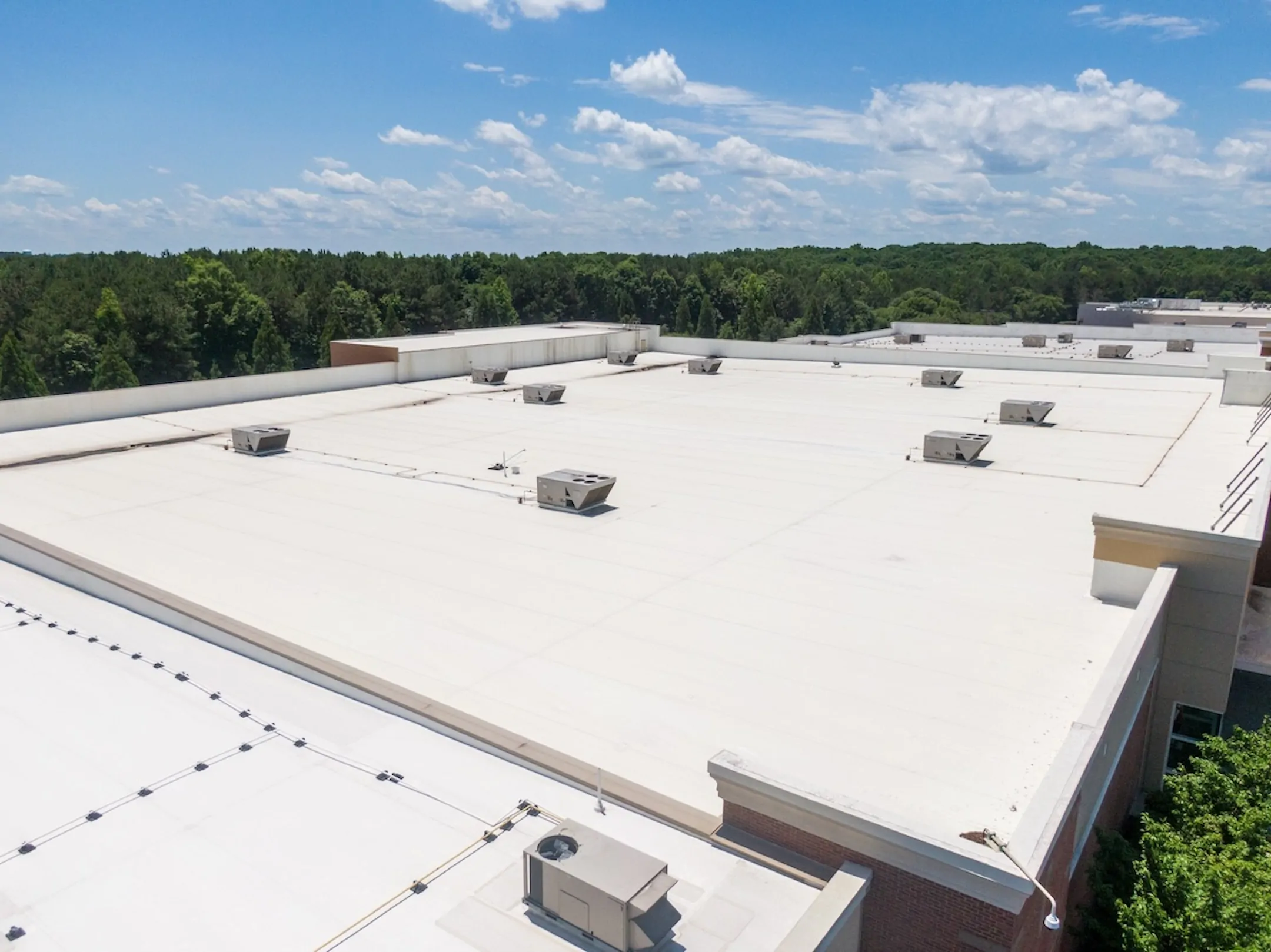 TPO commercial roofing system installed on a large industrial facility, featuring multiple HVAC units and specialized drainage.