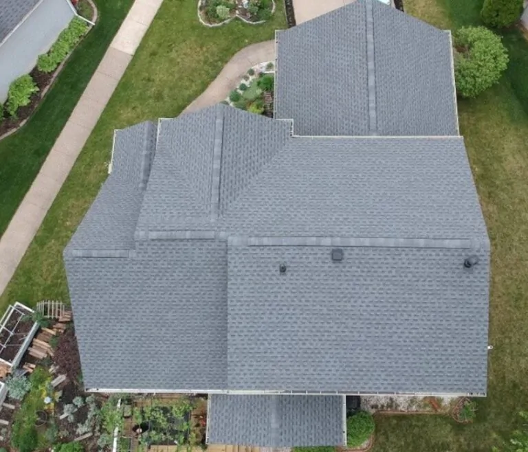 Top-down aerial view of a multi-level residential property showcasing an installed grey shingle roof with vents properly positioned along the ridges and slopes in Peoria, IL.