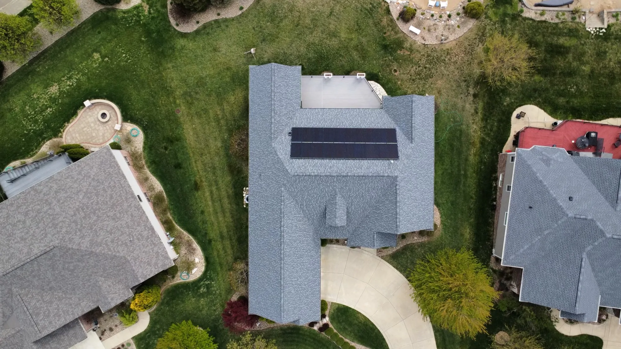 Aerial view of a high-quality shingle roof with solar panels installed by the ROOF TIGER team.