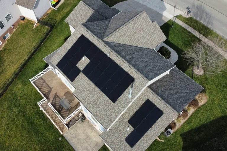Aerial perspective of a complex light green residential roof with many angles and corners and grey shingles.