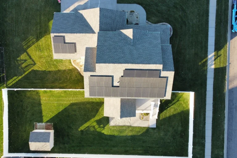 Extensive overhead perspective of a huge shingle roof system on a residential property, featuring multiple dark solar arrays.