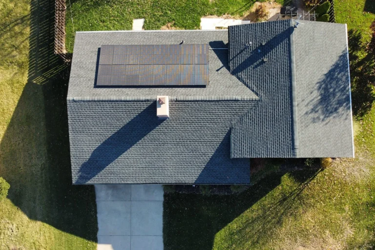 Vertical perspective of a modern home featuring an efficient array of solar panels installed on a dark grey roof.