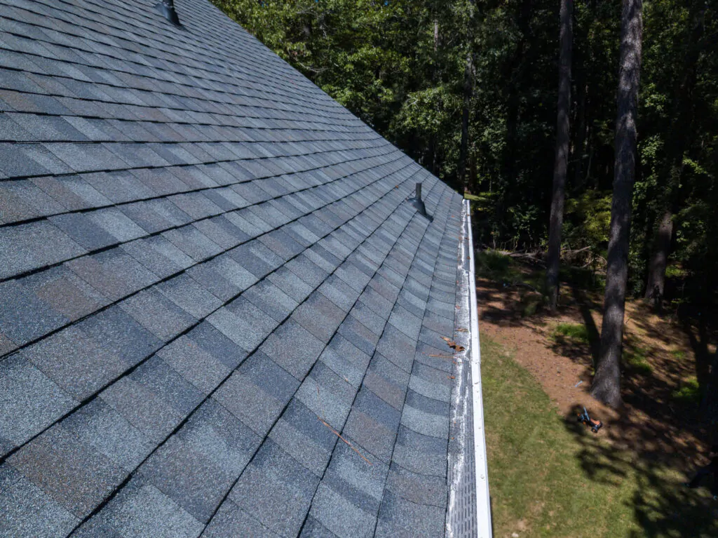 A wide-angle view of a professionally installed asphalt shingle roof by The Roof Tiger, featuring clean gutter lines and high-quality grey architectural shingles.