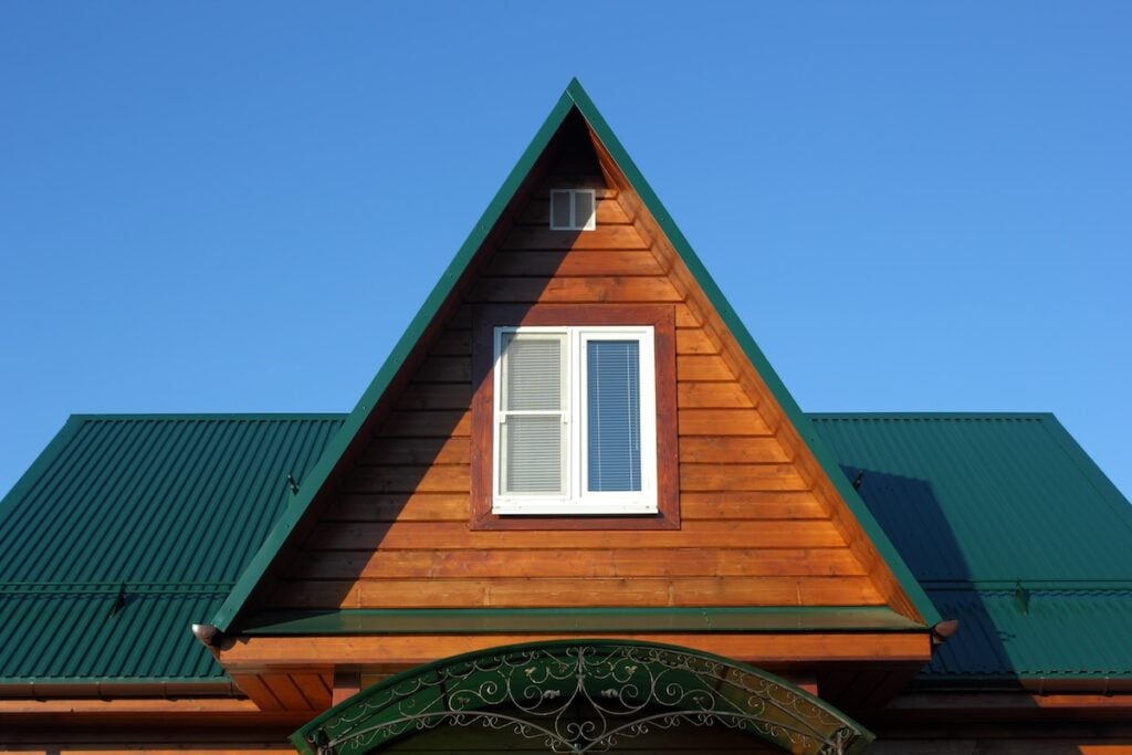 Green metal roof and attic window closeup photo