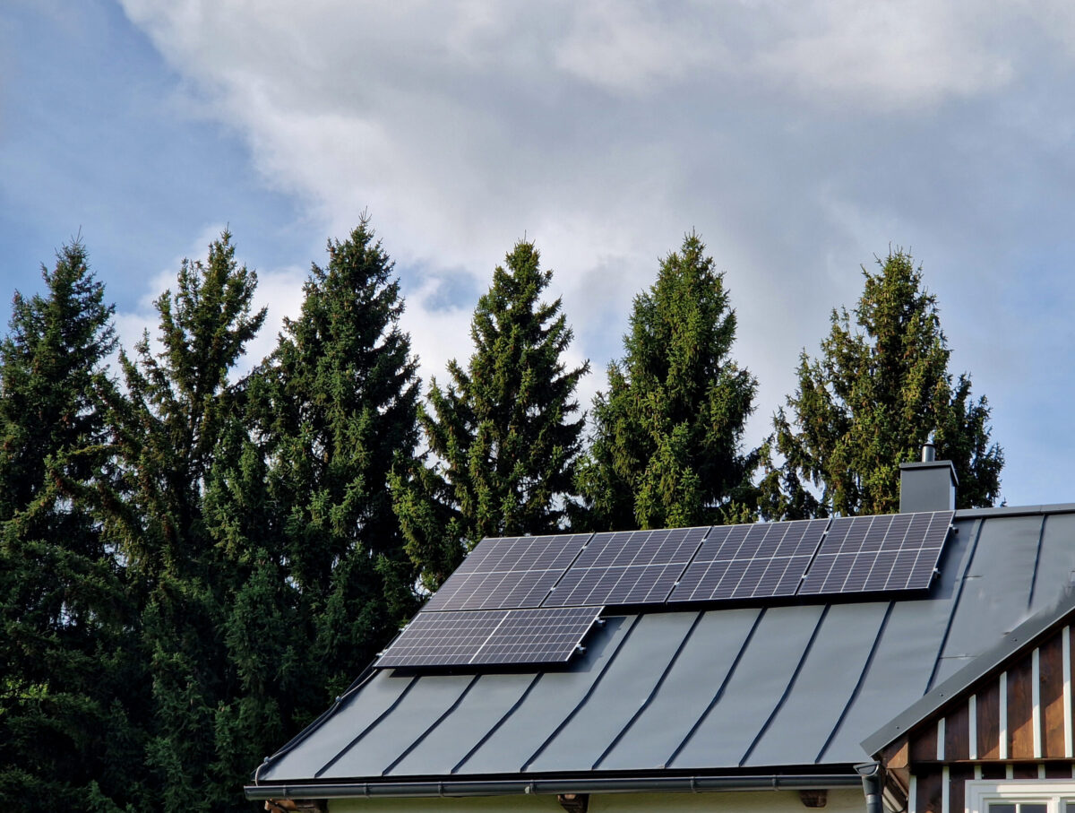 self-sufficient cottage house in the forest thanks to solar panels covering the roof in the mountains. production for own use. Scandinavian Nordic living alone, sheet metal roof