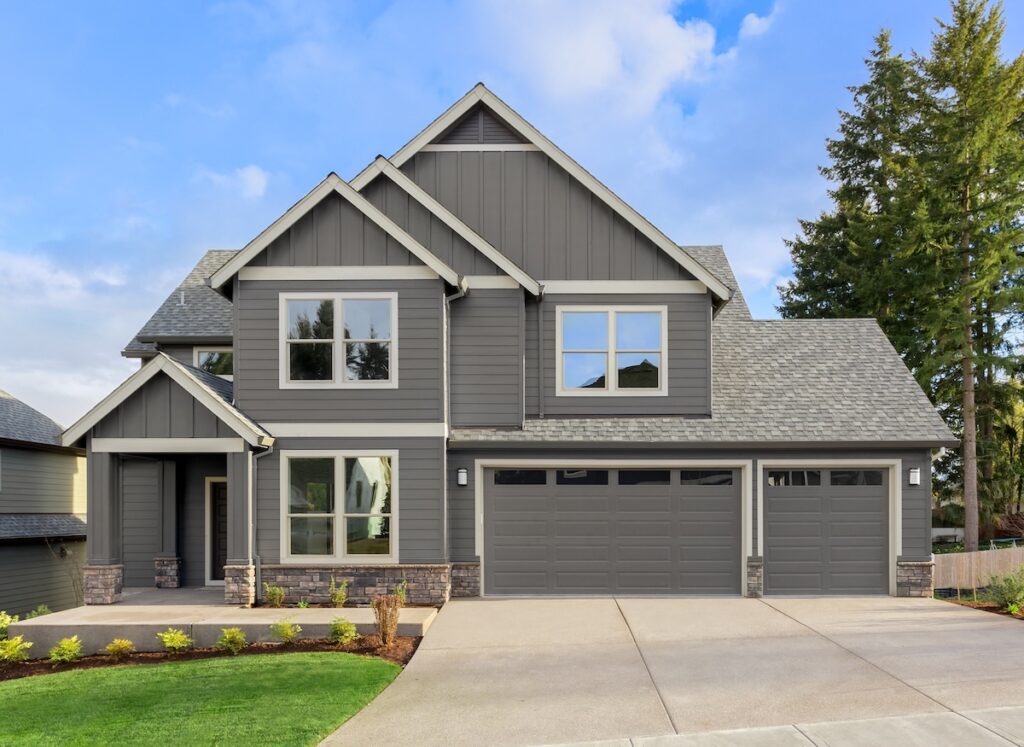 hip vs gable roof Front exterior of new home on sunny day. Features covered porch, three car garage, and gables