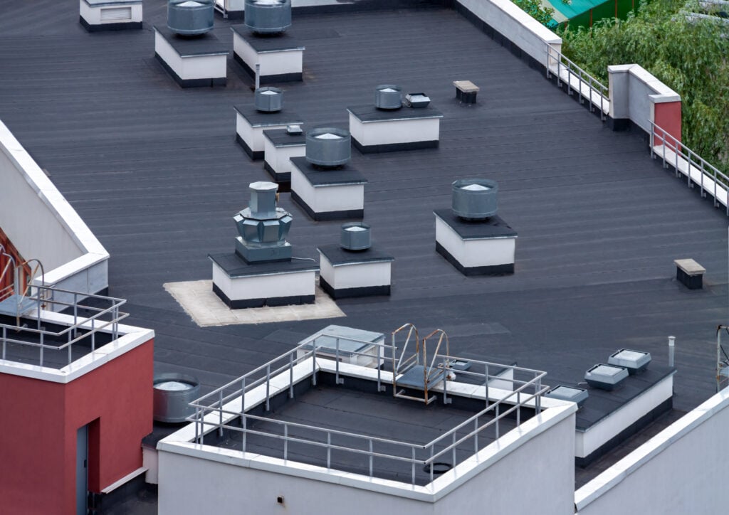 epdm vs tpo Top view flat roof with air conditioners and hydro insulation membranes on top of a modern apartment building summer day.