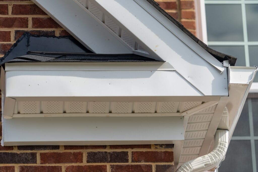 drip edge Gable with brick and vinyl siding, white frame gutter guard system, fascia, drip edge, soffit, on a pitched roof attic at a luxury American single family home neighborhood USA