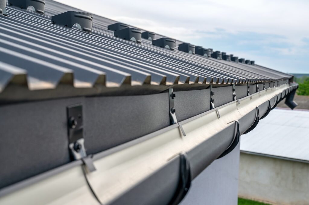 gutter installation Gutter system for a metal roof. Holder gutter drainage system on the roof.