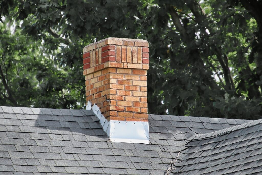 roof flashing repair An old chimney on a shingles rooftop.