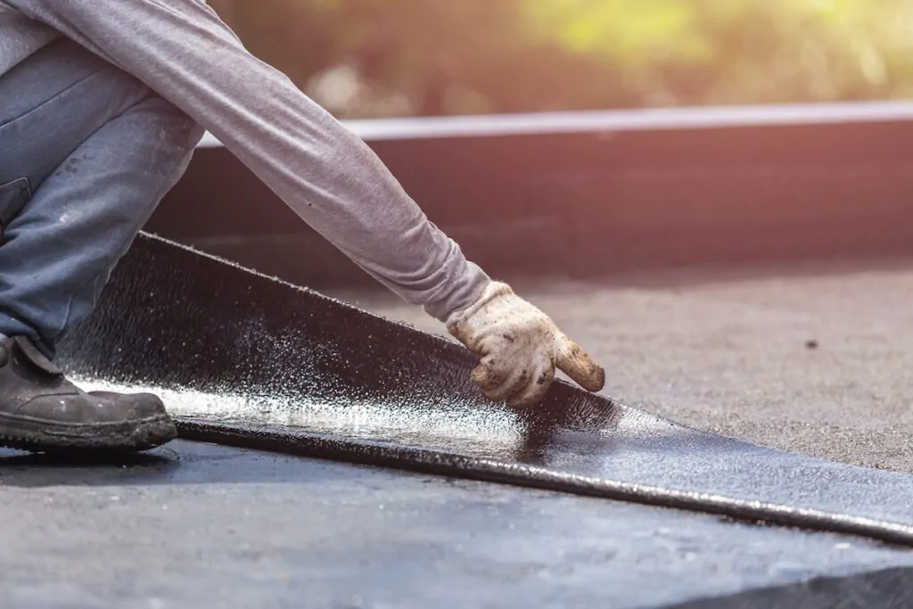 flat roof installation Asia worker installing tar foil on the rooftop of building. Waterproof system by gas and fire torching