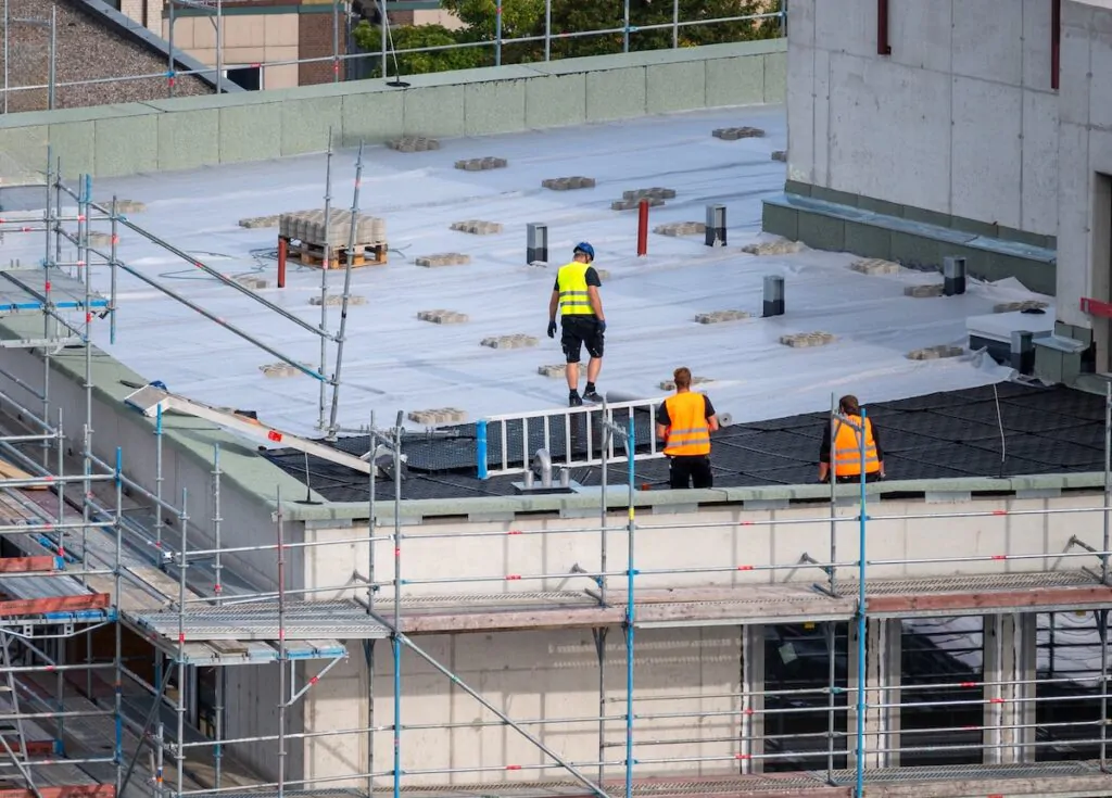 flat roof installation Birdseye view of roofer waterproofing the flat roof of a commercial building.