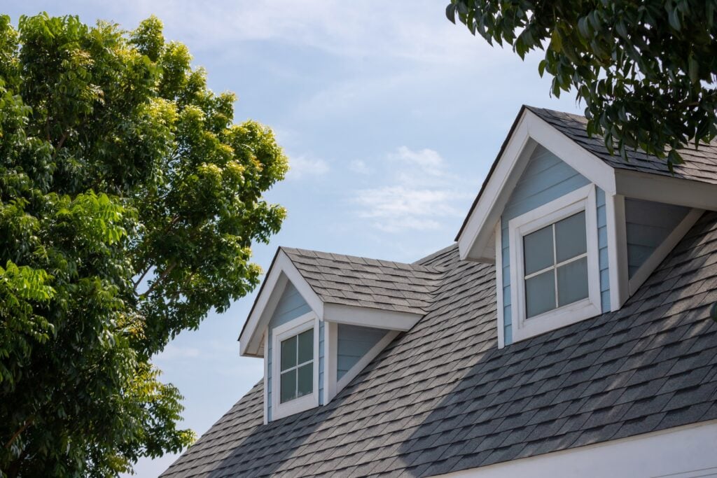 gaf roofing Roof shingles with garret house on top of the house among a lot of trees. dark asphalt tiles on the roof background