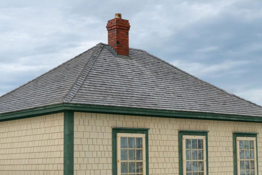 A vintage yellow cedar shake clapboard house with a grey shingled wooden hip roof