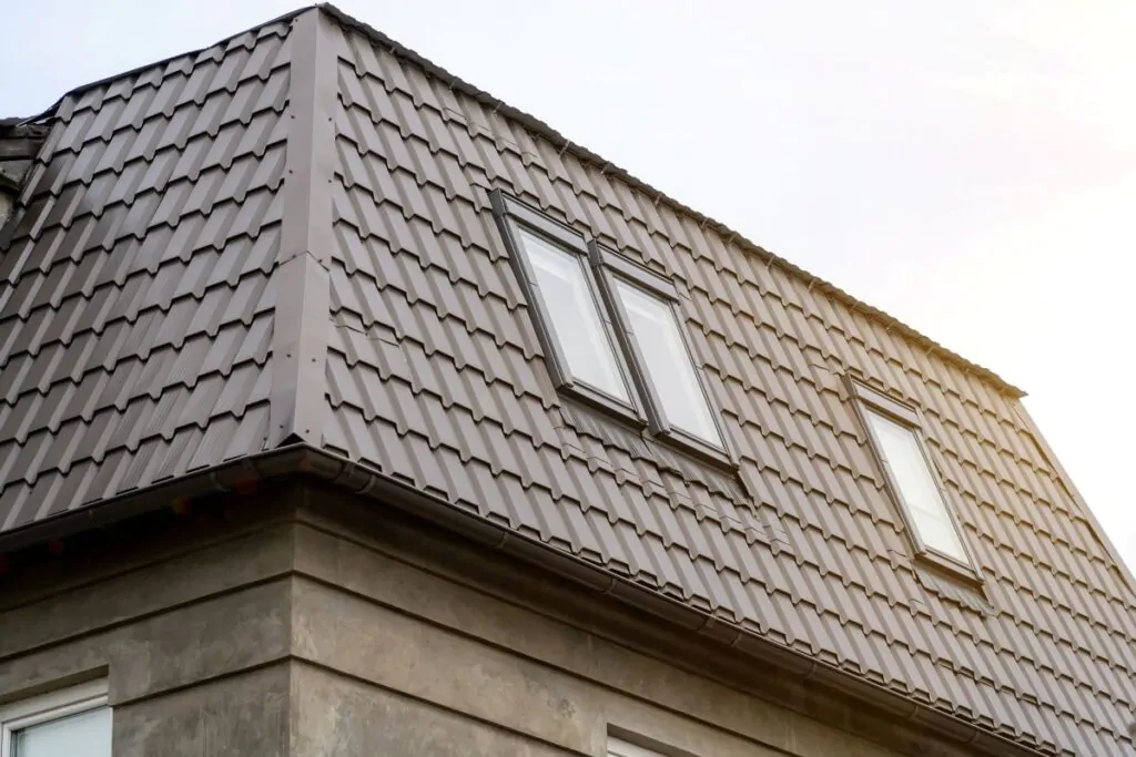 Mansard roof with metal coating of residential building with windows