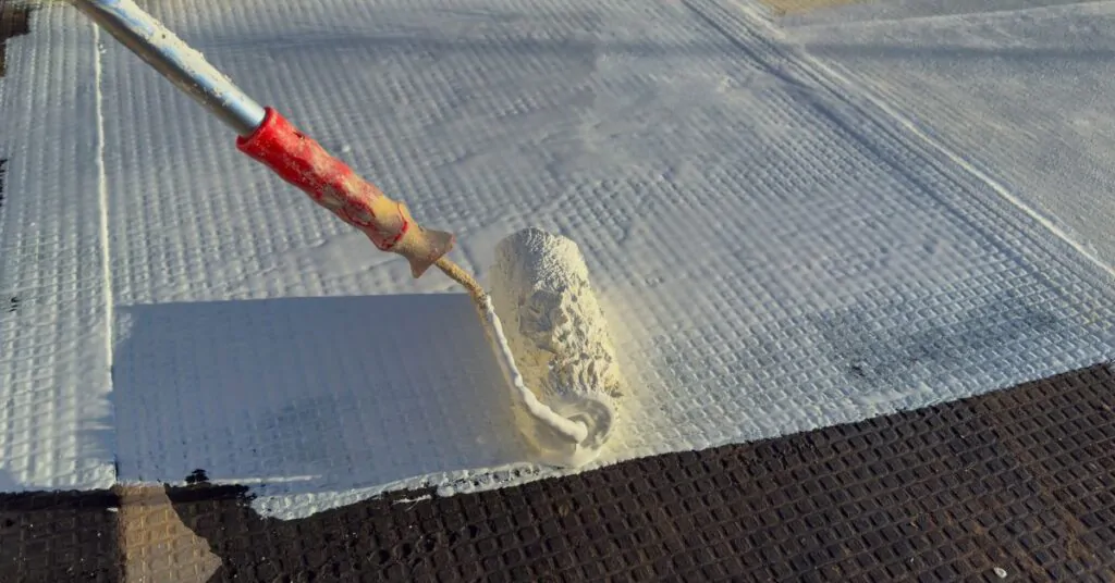Worker applying white polyurethane waterproof coating