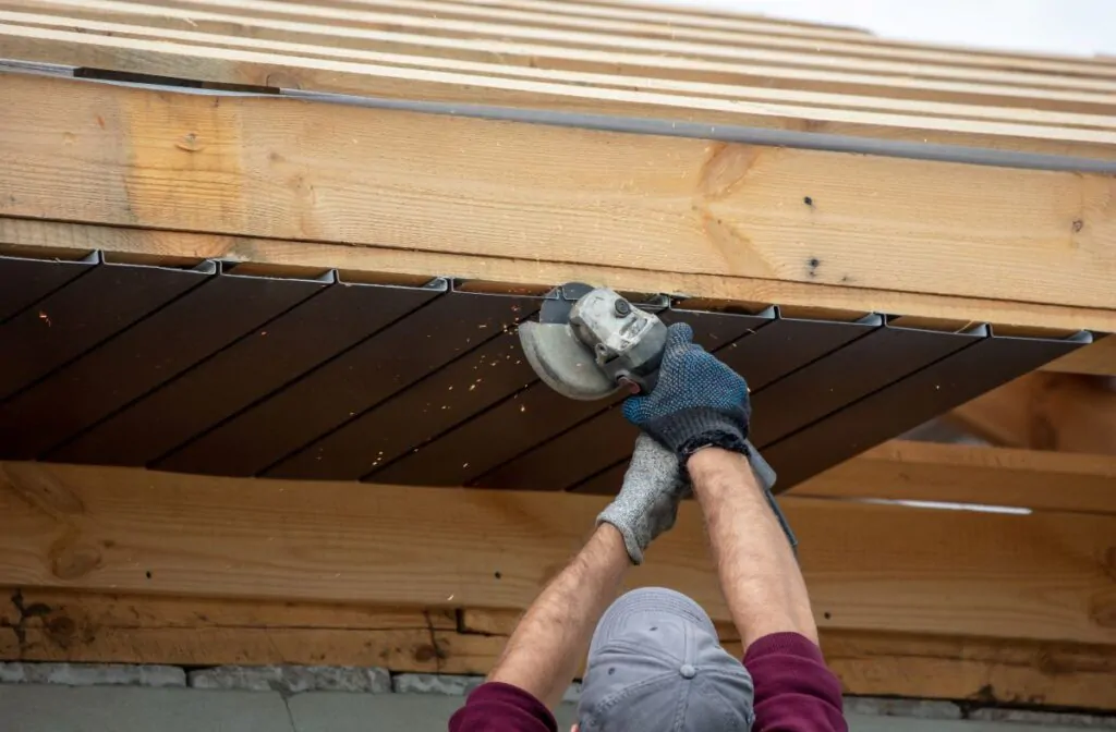 Workers trim the metal roof on the wooden roof