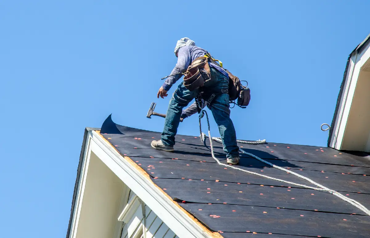 A member of Roof Tiger, one of the GAF roofing companies Peoria IL trusts, puts a new roof on a storm damaged home